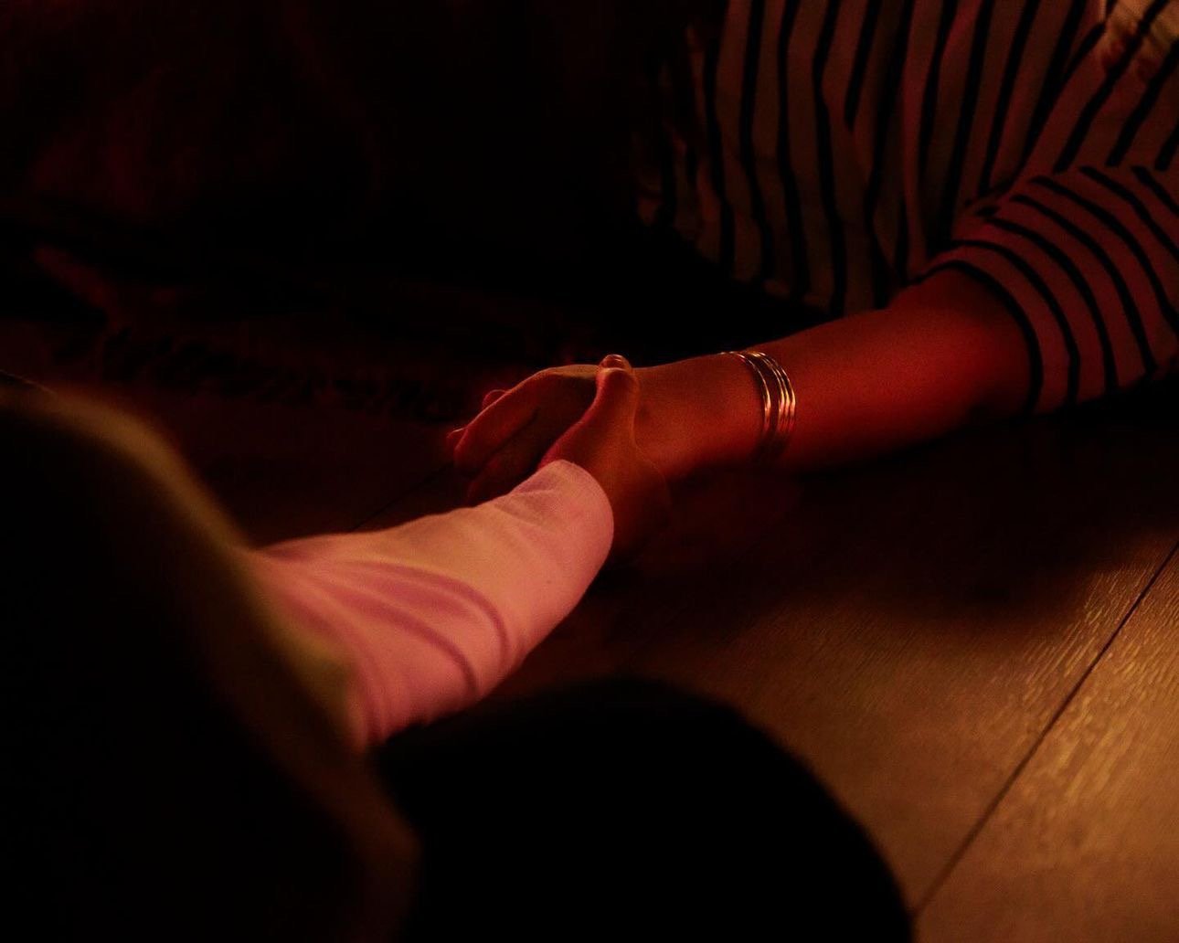 Two people holding hands during an emotional moment in a breathwork session