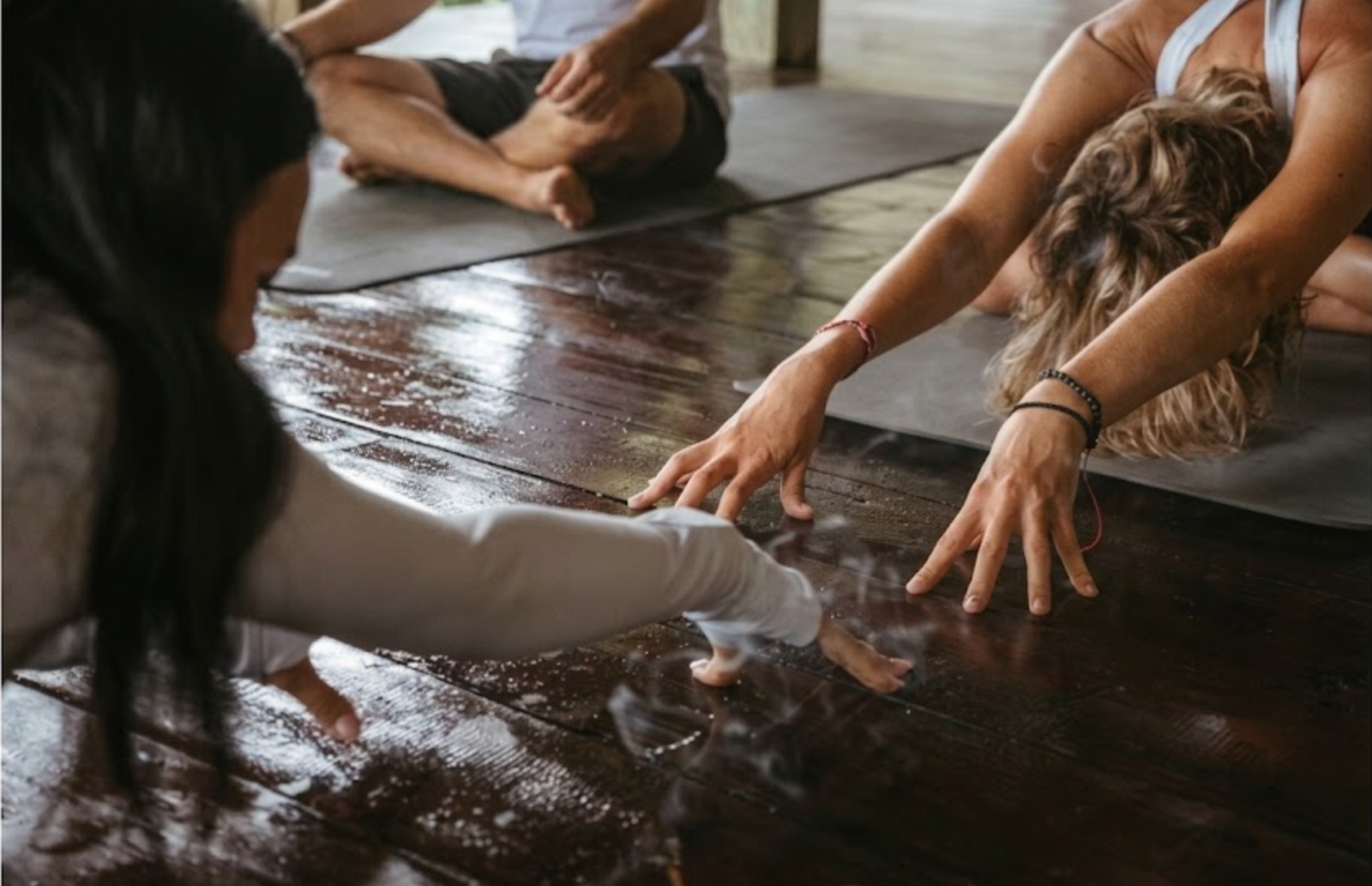 Group breathwork class reaching hands down to the floor together